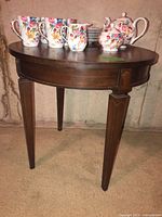 Full view of round wooden side table with contents on top (not included)