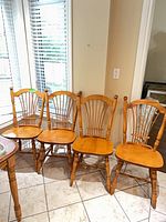 Four maple spindle-back chairs against wall