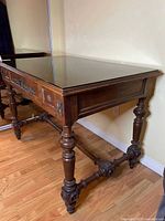 Full view of antique wooden writing desk with glass top and carved legs