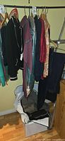 Clothing rack showing multiple garments on hangers and additional clothes in shopping bag