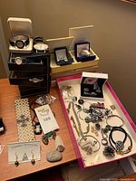 Overview of assorted jewelry pieces, watches, boxes on table