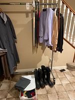 Full view of rack with jackets, umbrellas, rubber boots, bin of accessories
