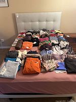 Overview of folded clothing pieces spread on bed