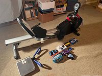 Overall view: rower-bike, scale, thigh toner, assorted weights on floor