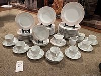 Full set laid out on carpet showing plates, bowls, cups, saucers, sugar bowls, creamer