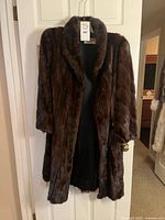 Front view of brown fur coat hanging on door
