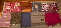 Overview of ten scarves and stoles laid out showing colours and packaging