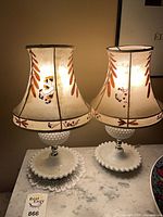 Both milk glass table lamps lit on marble top showing full view