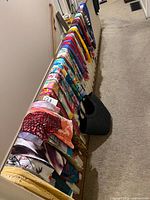 Long view of multiple silk scarves draped over railing, showing variety of colors and patterns
