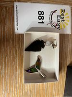 Open box showing arrowhead pendant and whale-tail pendant