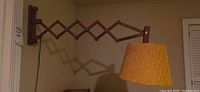full view of teak scissor-arm wall lamp extended with shade