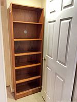 Full front view of tall teak veneer bookcase showing six shelf positions