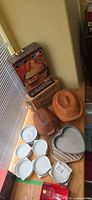 Overall lot showing terracotta bakers, white ceramic dishes, heart pan and boxes