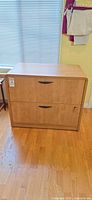 Front view of two-drawer wood laminate lateral filing cabinet showing handles, lock with key, overall appearance
