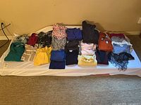 Overview of approx. 20 folded garments laid out on a mattress