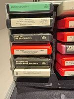 Left column of 8-track tapes inside case showing titles and colours