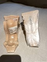 Front view of both wood corbels, one fully wrapped, one partially unwrapped