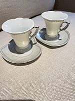 two white porcelain espresso cups with matching saucers