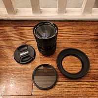 Sigma lens with Nikon cap, filter and hood on wooden surface