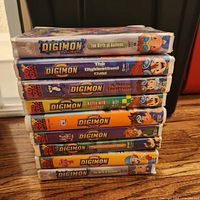 Stack of ten Digimon Fox Kids Video VHS tapes showing visible titles and slipcase condition