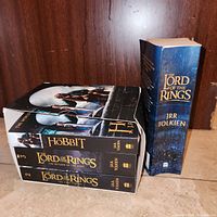 Boxed set of three movie-tie-in paperbacks and separate single-volume Lord of the Rings shown on floor