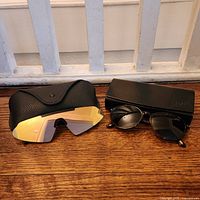 Two cases side by side, Persol case with sunglasses partially visible, L.A. Express case with stack of colored shield lenses