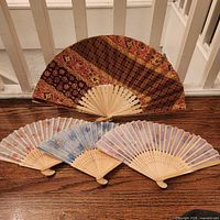 Four folding fans displayed, showing fabric and paper designs and bamboo ribs
