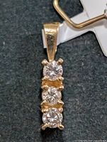 Front view of 14K gold pendant showing three diamonds in vertical alignment