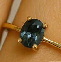 Close-up of blue oval diamond in gold ring on finger