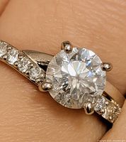 Ring on finger showing centre diamond and side stones