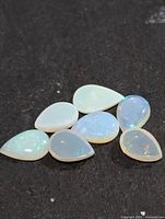 Six pear-shape opals on black background