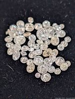 Pile of small loose round diamonds on dark background