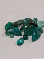 Loose emerald gemstones assorted on white surface