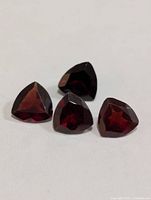Four trilliant-cut garnets grouped together on neutral background