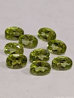 Ten oval peridot gemstones arranged on surface