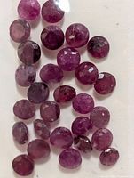 Group of loose round faceted rubies inside plastic sleeve