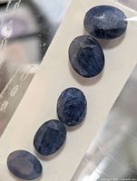 Five oval blue sapphires on card
