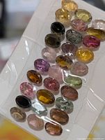 Front view of all 25 faceted oval tourmaline gemstones in plastic strip