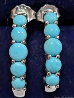 Front view of both earrings showing turquoise cabochons and silver prongs