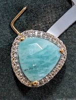 Front view of silver pendant displaying blue triangular gemstone and surrounding clear stones