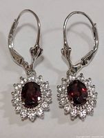 Front view of both earrings showing garnet centers and CZ halo