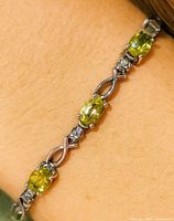 Close-up of bracelet on wrist showing peridot and diamond stations