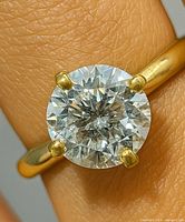 Close-up of ring on finger showing moissanite and yellow gold band