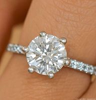 Close-up of 14K white gold ring on finger highlighting round moissanite and pavé band