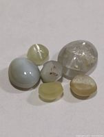 Six small cat’s eye cabochon gemstones displayed on white surface