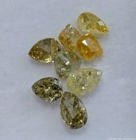Nine pear-shape loose diamonds in varied fancy colours on white background