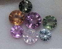 Close-up of seven faceted sapphires showing colors and cuts