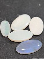 Five oval opal cabochons on dark surface
