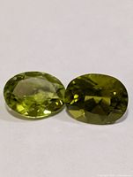 Two green oval faceted gemstones side by side