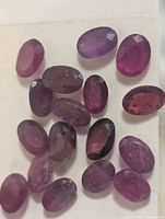 Group of loose oval faceted rubies on white background
